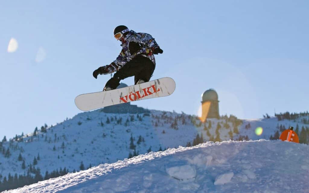 Snowboardfahrer im Sprung auf der Piste im Familienskigebiet Großer Arber